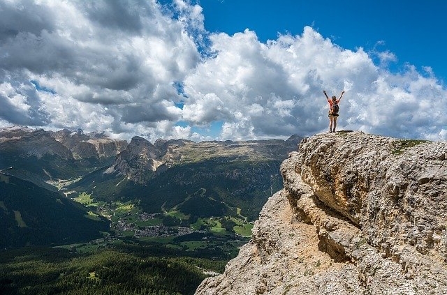 Woman on mountain top raises arms in victory